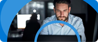 Hombre trabajando muy concentrado en un portátil en una oficina con luz tenue.