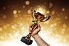 An image showing a hand holding a trophy