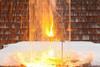 A sparks and bright flash of hot material in a terracotta flowerpot held in a laboratory clamp and stand. The set up is outside with some snow behind a protective clear screen