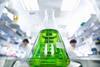 A glass conical flask of green liquid in a lab setting