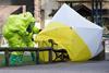 Two people in Hazmat suits around a bench covered in plastic