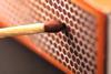 A close-up photograph of a brown match head held against the side of a match box ready to be struck