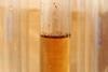 A close-up photograph of a glass test tube containing a light brown liquid