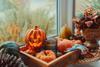 Autumnal pumpkins on a windowsill and one shiny pumpkin decoration with a face 