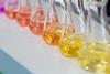 Six conical flasks containing coloured liquid from yellow through to pink