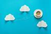 Photograph of coffee cup on blue paper with paper clouds around it and a string swirling away from it suggesting it flying through a sky between the clouds