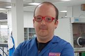 A man in a blue lab coat with red glasses in a modern laboratory