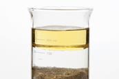 Photo of oil, water and sand separated in a beaker