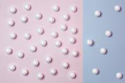 A photo of white balls on a blue and pink background. There are more balls on the pink background than the blue.