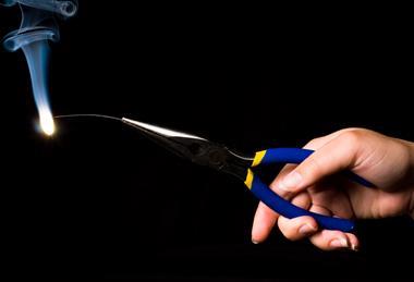 A photograph of a person's hand holding some burning magnesium wire in a pair of pliers