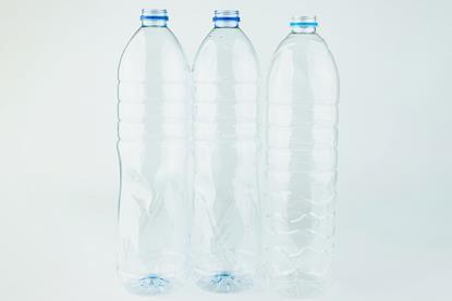 Three clear empty plastic drink bottles, against a plain white-grey background