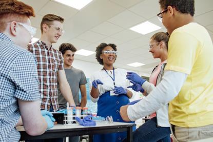 Students and teacher gather around a chemistry classroom laboratory bench