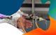 The hand of a teacher in a lab coat gestures towards a Liebig condenser used for distillation