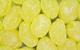 A close-up photograph of yellow boiled sweets dusted with white sugar