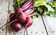 picture of five beetroots with leaves on a wooden floor
