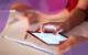 A close-up of a student's hands as they use a tablet to zoom in on a copy of the periodic table