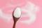 Sugar on a wooden spoon with a pink background