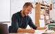 Photo of a teacher sitting at a desk in a classroom and marking pupil's work