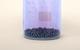 Solid iodine crystals in a glass beaker, with a purple vapour visible as sublimation occurs
