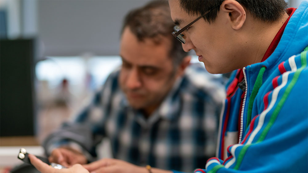 Two people examining a device together at a table.