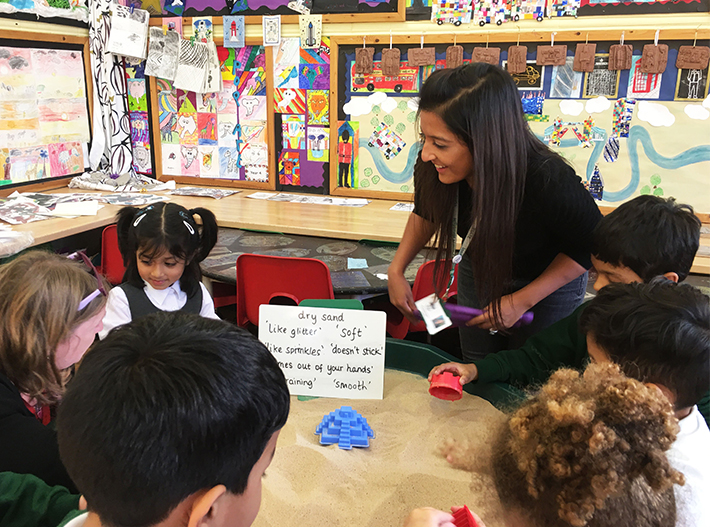 Teacher helping children with sand activity