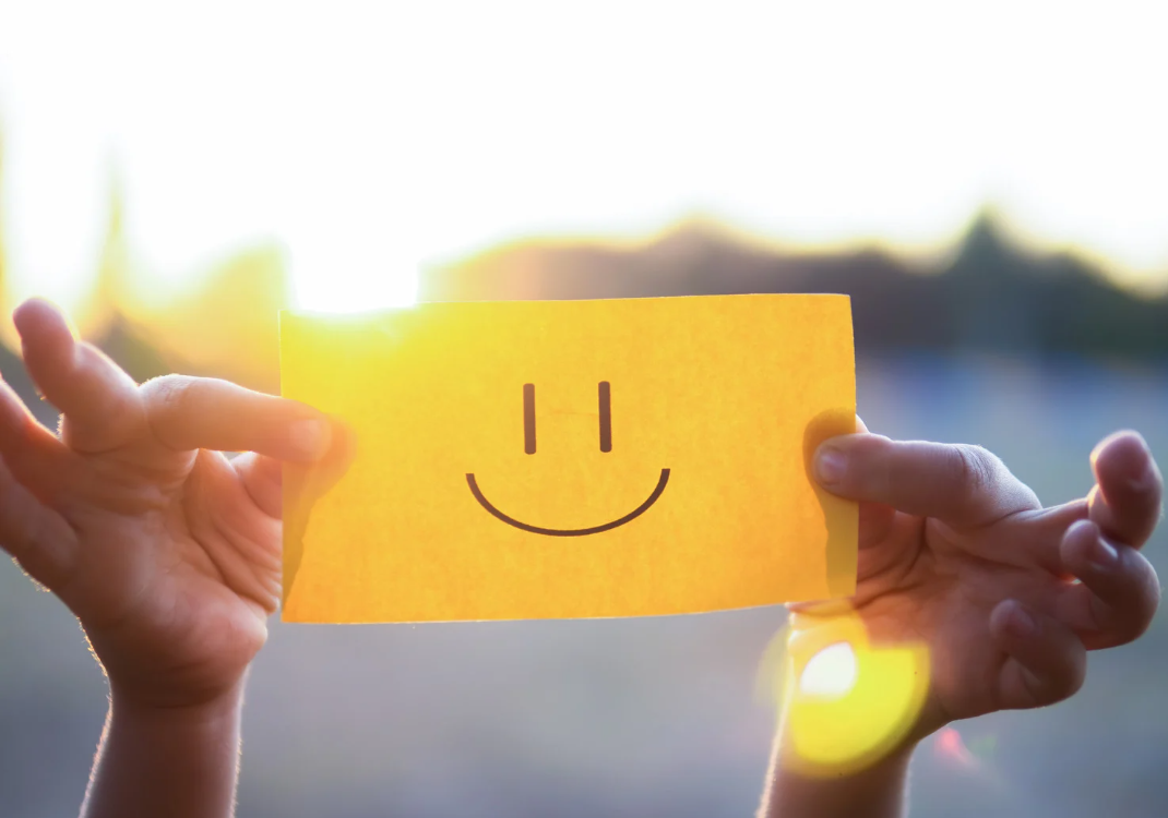 Une personne montre un post-it avec un smiley 