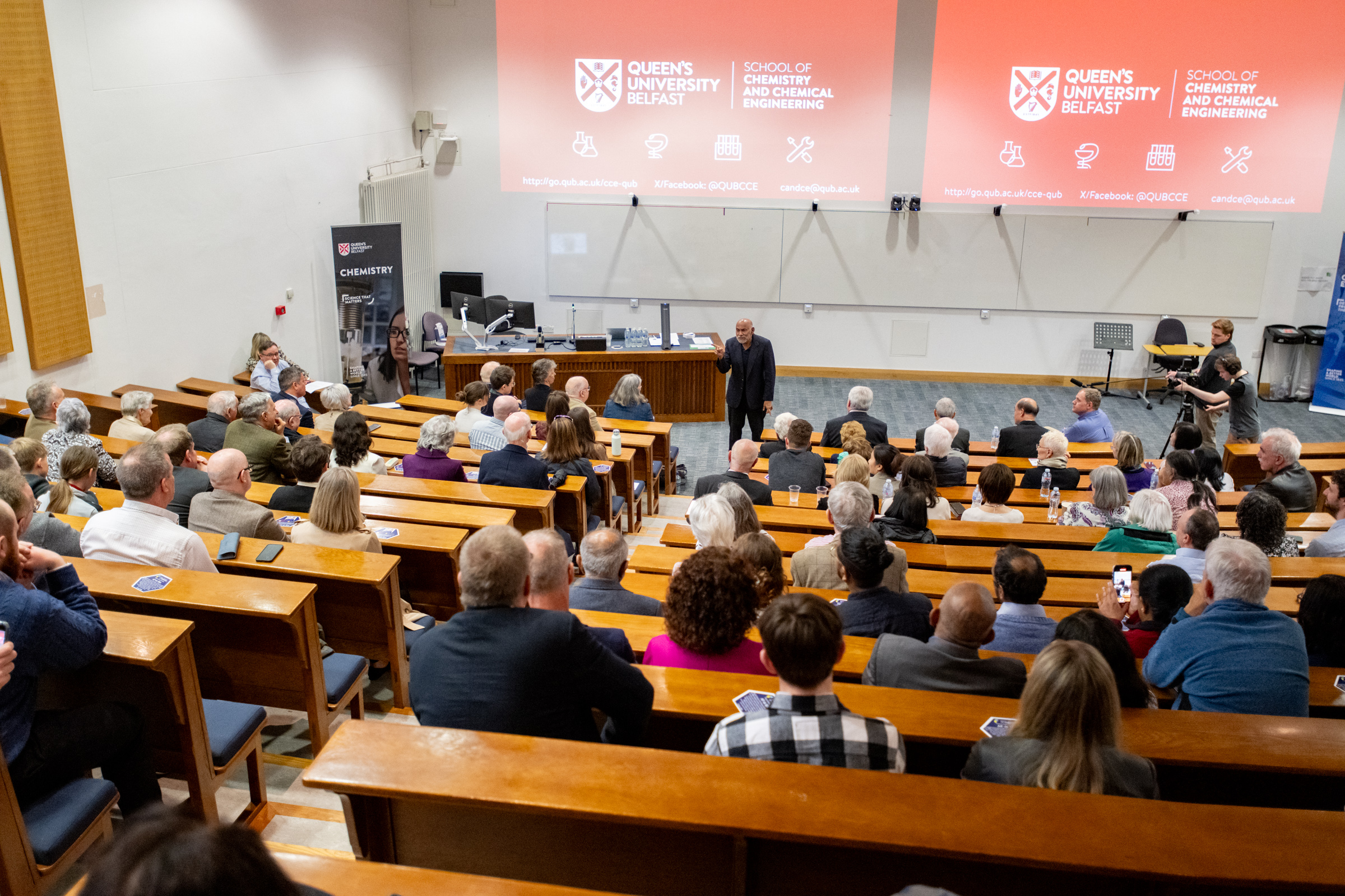 Hundreds of people watch Prof AP de Silva give a speech in a lecture hall at Queen's University Belfast after the unveiling