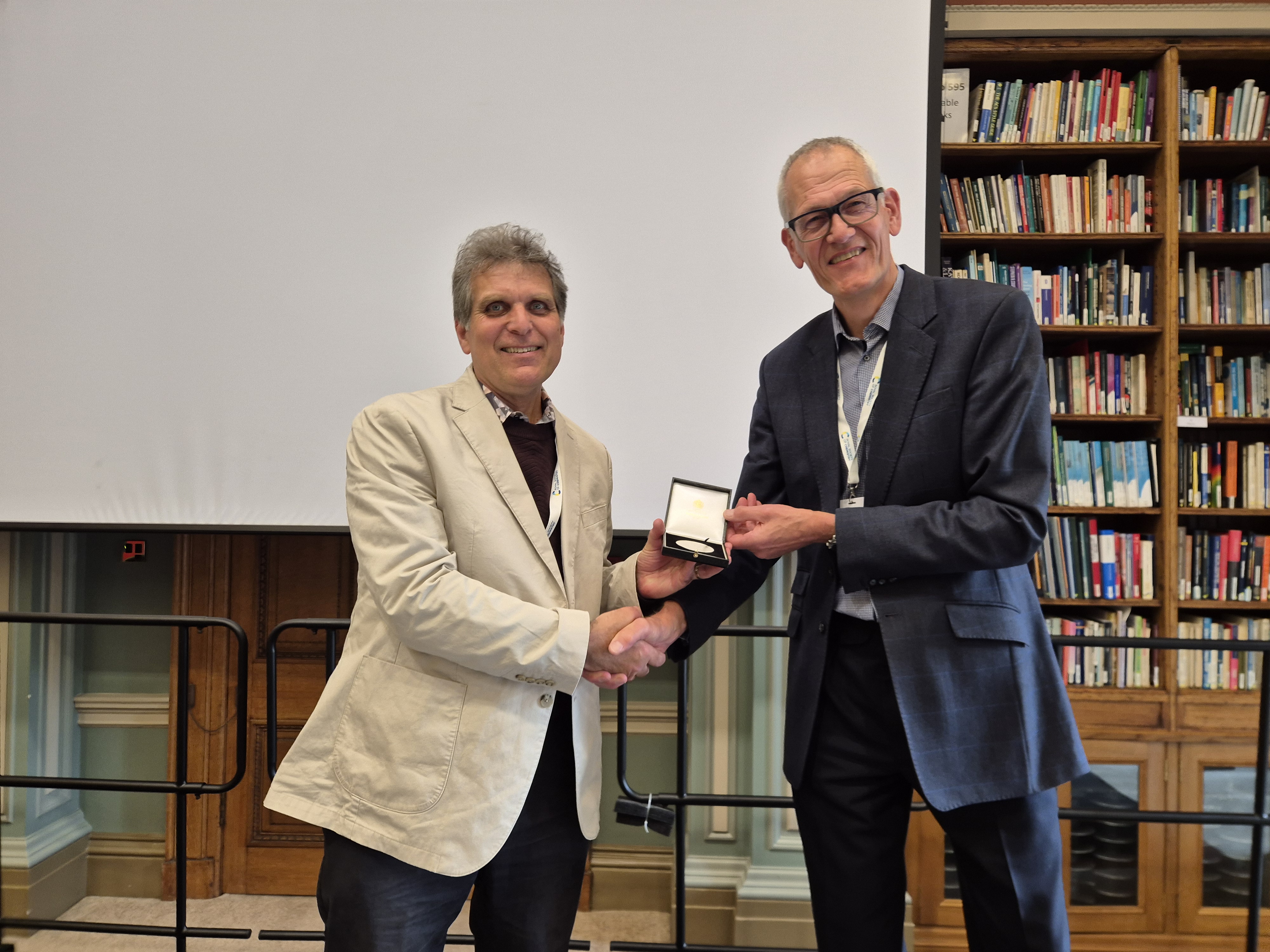 Professor Mark Bradley (left) receives his CBIC Presidential Medal and shakes hands with Dr David Andrews
