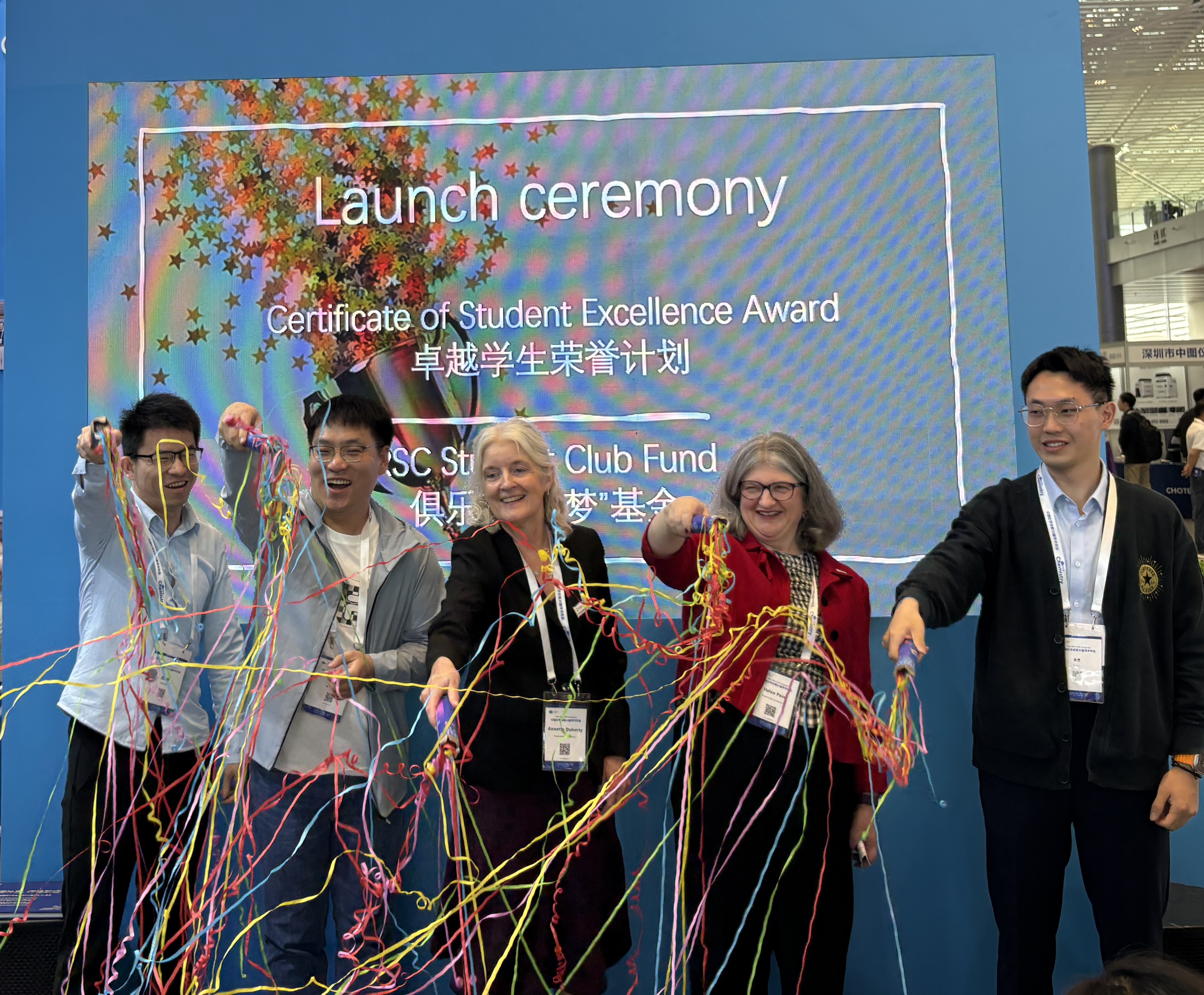 Dr Annette Doherty (middle) and Dr Helen Pain (second right) wave colourful streamers alongside three other individuals at a launch ceremony in China