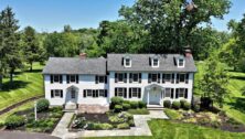 Large colonial property with black shutters and white siding.