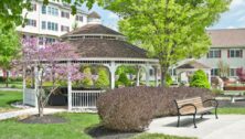 A gazebo, trees, park benches, bushes and a pathway outside Freedom Village at Brandywine retirement community.
