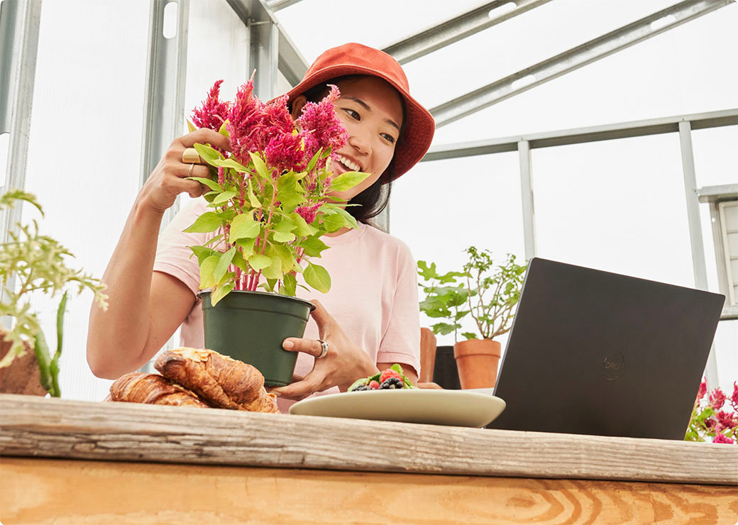 Mulher trabalhando com uma planta olhando para um notebook