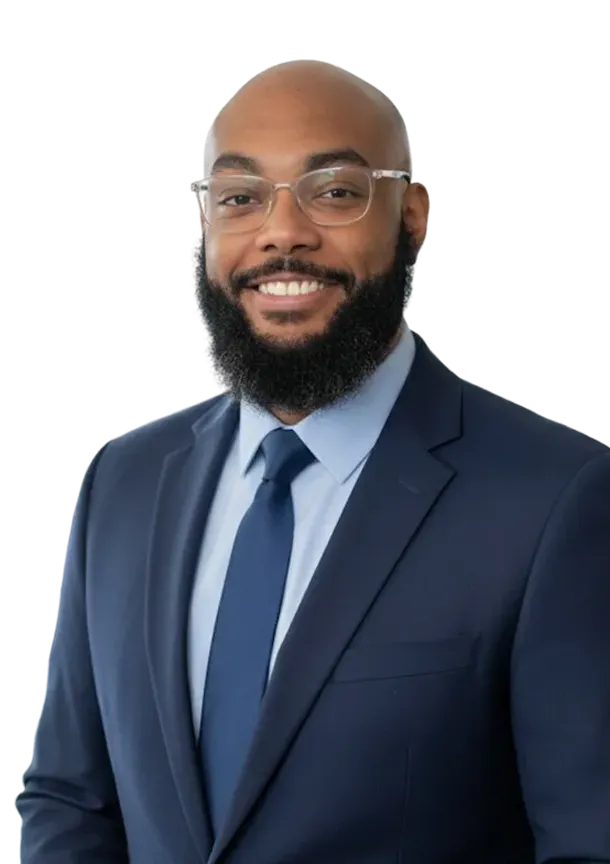 Smiling bald man with glasses and a full beard wearing a navy blue suit, light blue shirt, and dark blue tie.