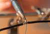 Two black wires being soldered together using a soldering iron