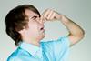 A man holding his nose with a disgusted expression