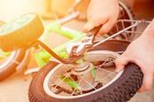 An adult using a spanner to remove training wheels from a child's bike