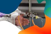 The hand of a teacher in a lab coat gestures towards a Liebig condenser used for distillation