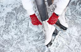 Someone tying up their ice skates while sitting on ice