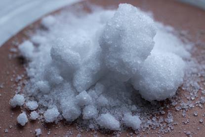A close-up photograph of white or translucent crystals of the alkali metal salt sodium nitrate