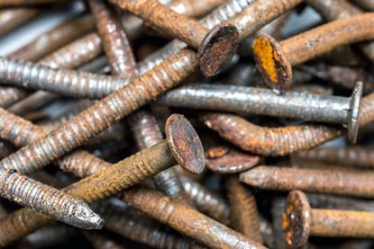 A close-up photograph of a pile of rusty metal nails