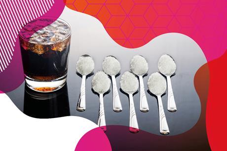 Photo of a glass of cola with ice in. Next to the glass is seven teaspoons with sugar on.