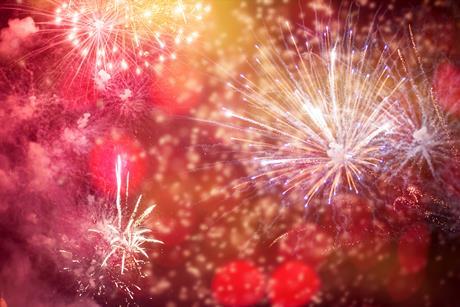 A photograph showing red, orange and blue fireworks during a night-time display.