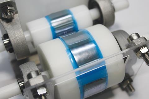 Two rollers with sticky tape on spread out a silvery substance in to a fine layer