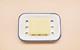 A photograph of a bar of yellow soap in a blue and white enamel soap dish, against a pink-orange background