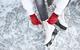 Someone tying up their ice skates while sitting on ice