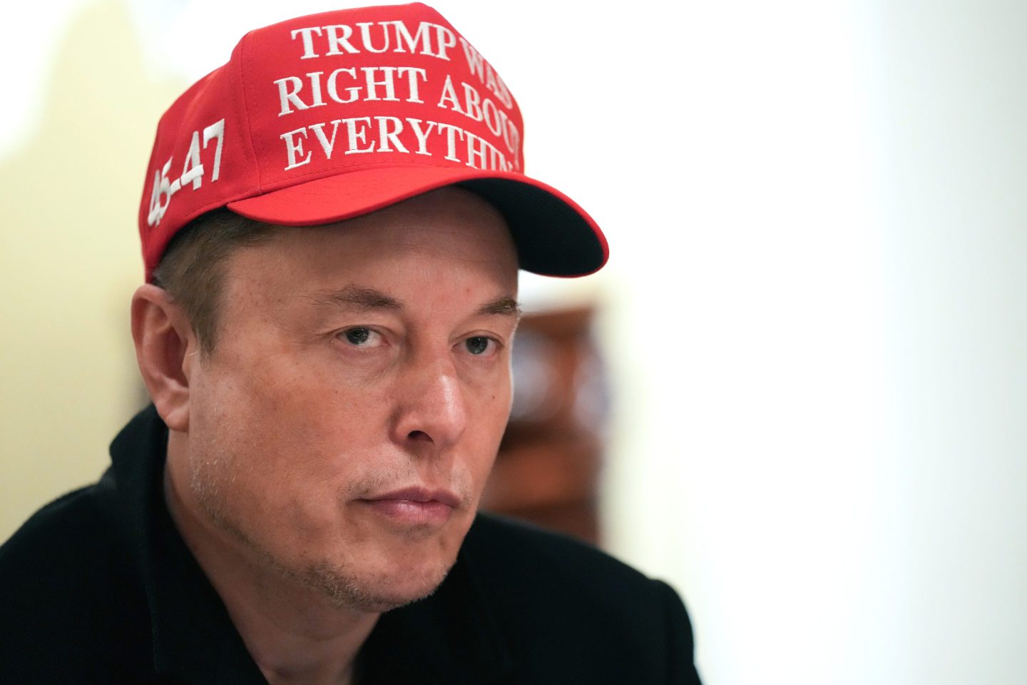 Elon Musk wearing a red "Trump was right about everything" trucker-style hat