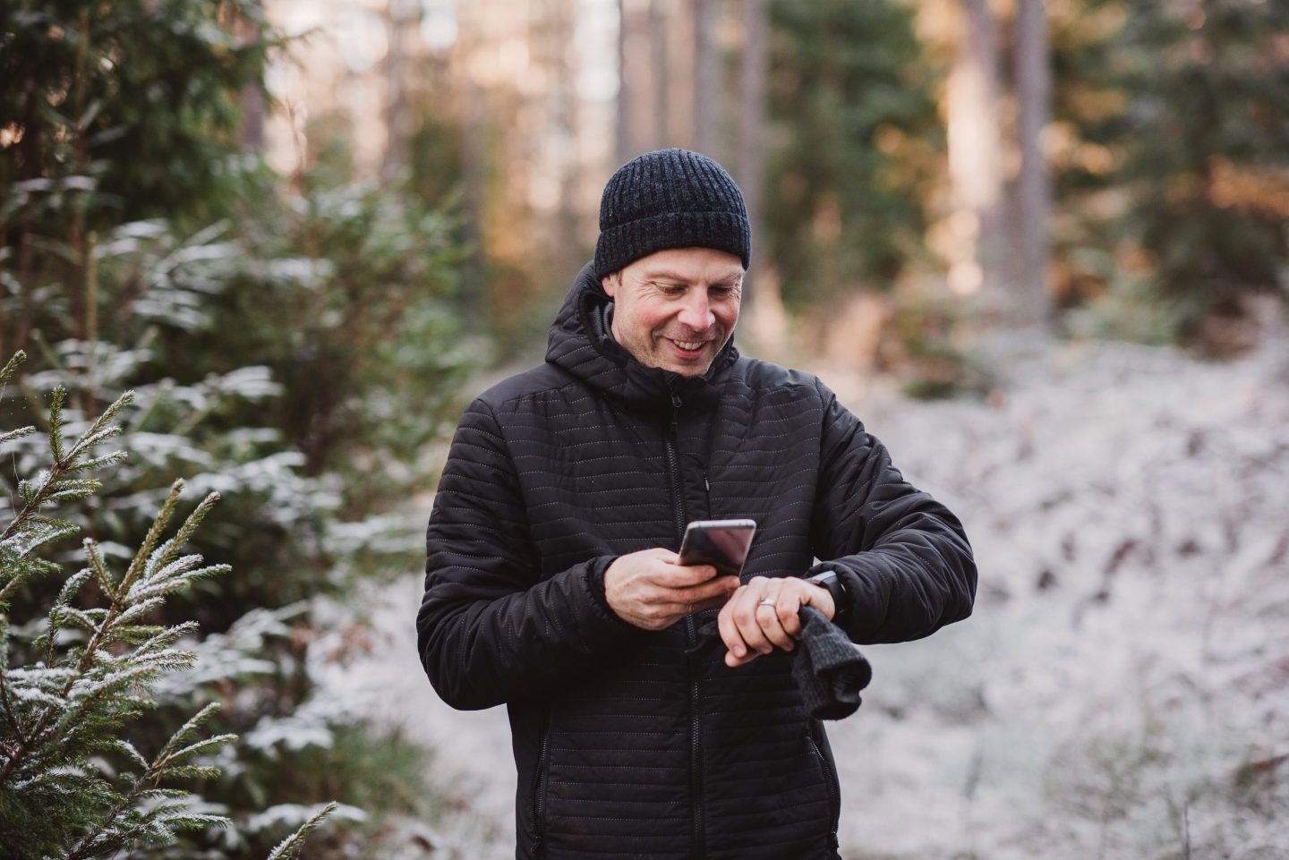 Man checking watch as he walks through forrest