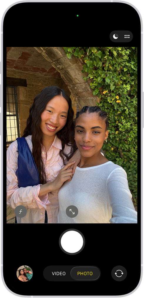 Ecrã da Câmara no modo Fotografia. No enquadramento da câmara, as pessoas estão a tirar uma selfie.