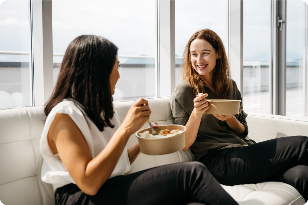 Two women eating lunch on a couch