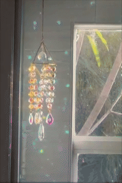 Crystal wind chime hanging by a window, casting sparkles and light reflections, creating a decorative and calming effect